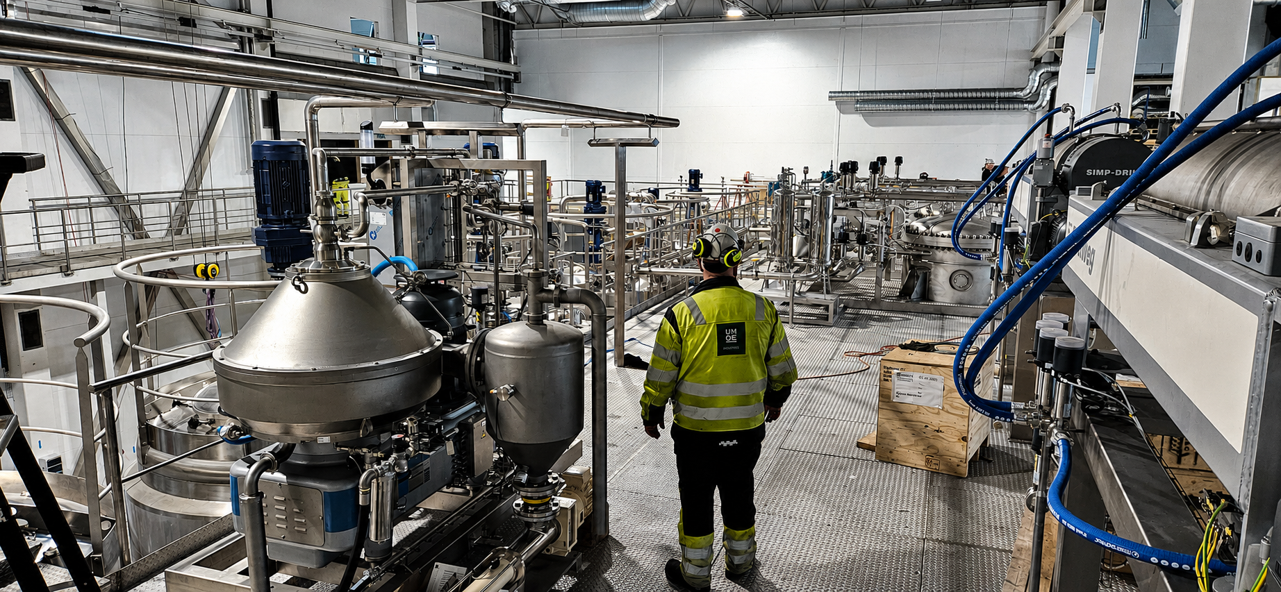 Umoe Industries technician walking through a stainless steel process hall with separators and piping