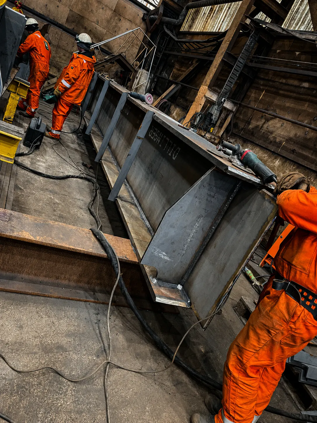 Welders grinding and fitting a prefabricated steel structure in the workshop